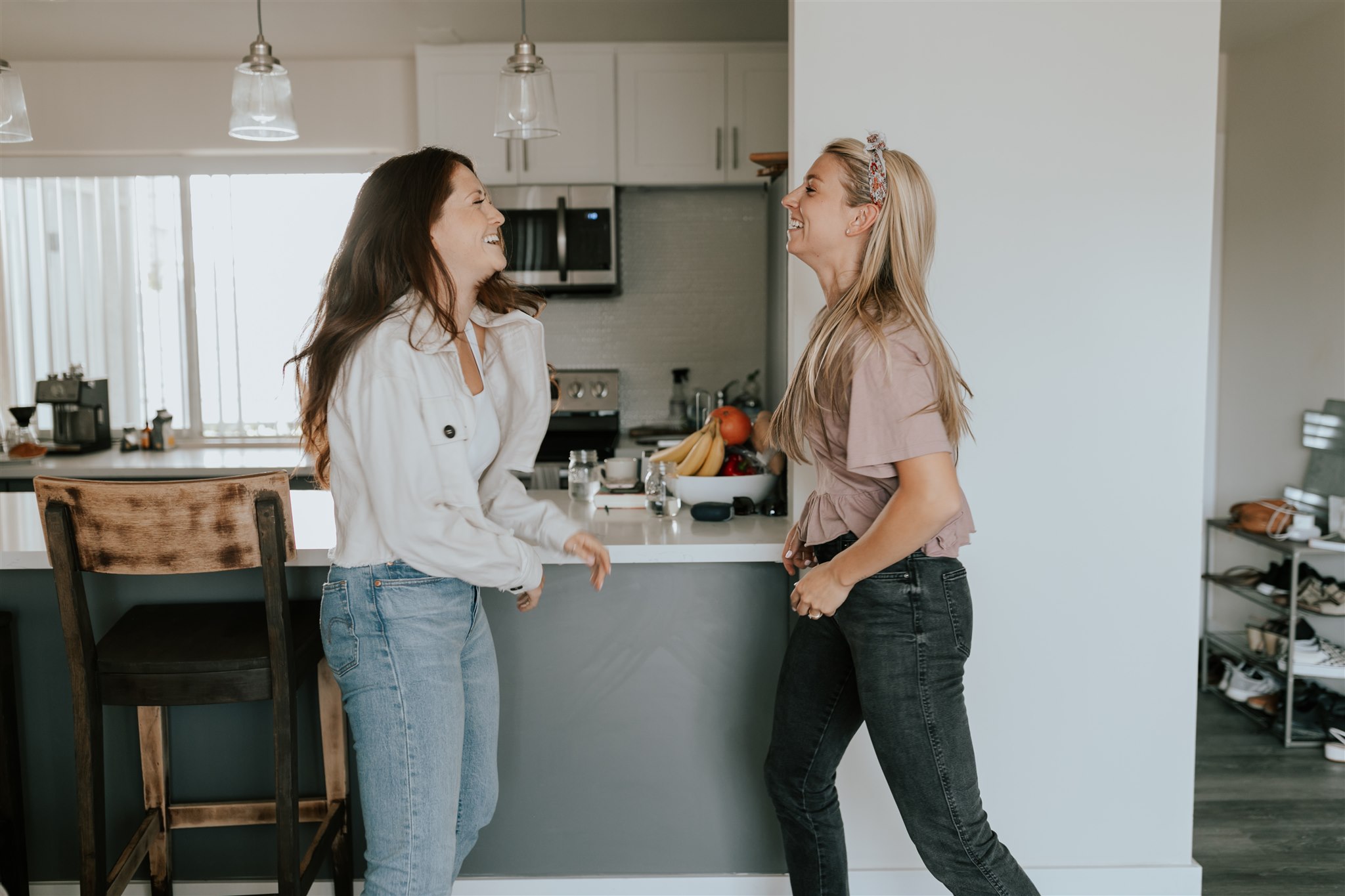 Two young women greet each other inside a house.